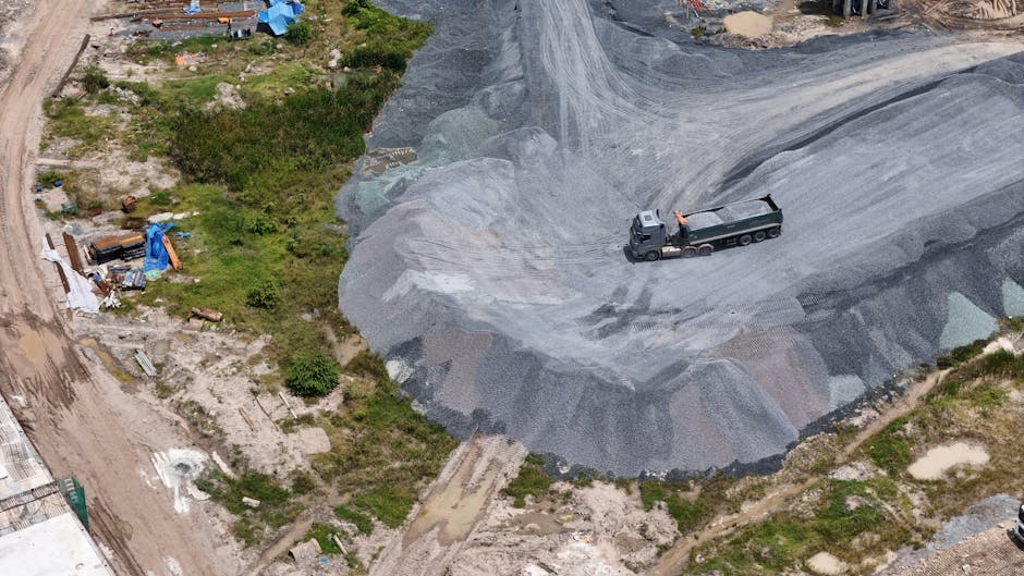 Aerial shot of a construction site with a truck on gravel piles, showcasing industrial activity.